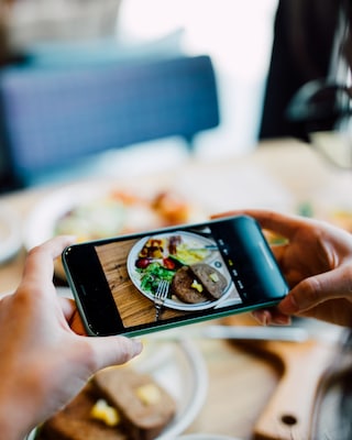 Donna che fotografa il suo cibo con il cellulare in un ristorante