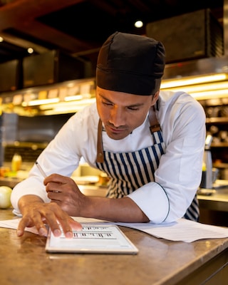 Uno chef in un ristorante guarda una ricetta online su un vassoio 