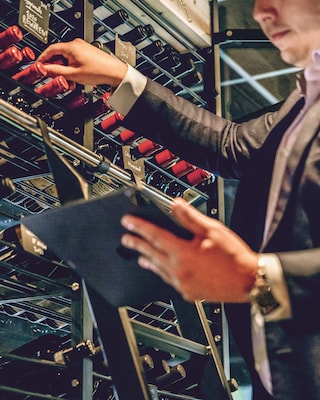 Justin usa il tablet e la lista dei vini per trovare il vino giusto dallo scaffale.