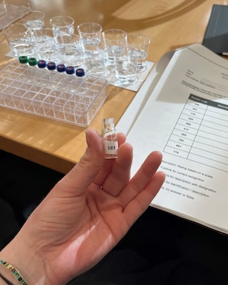 Hand holding a small testing glass containing a liquid