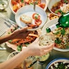 Diverse mani prendono il cibo dai piatti pieni